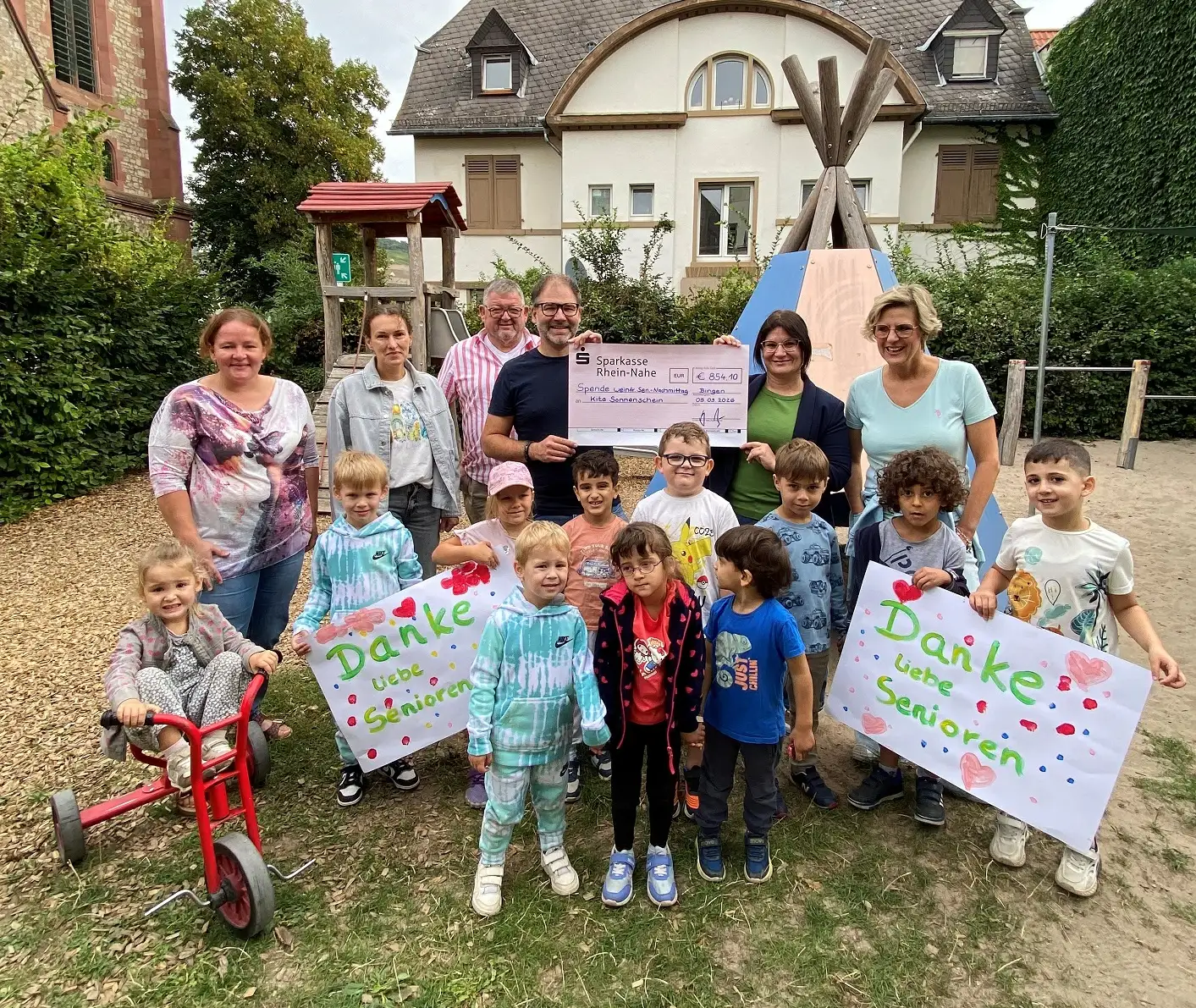 Kinder der Kita Sonnenschein bei der Scheckübergabe mit Beigeordnetem Sebastian Hamann, Amtsleiter Ralf Klingler, Alexandra Decker und Moderatorin Nicole Kierdorf.