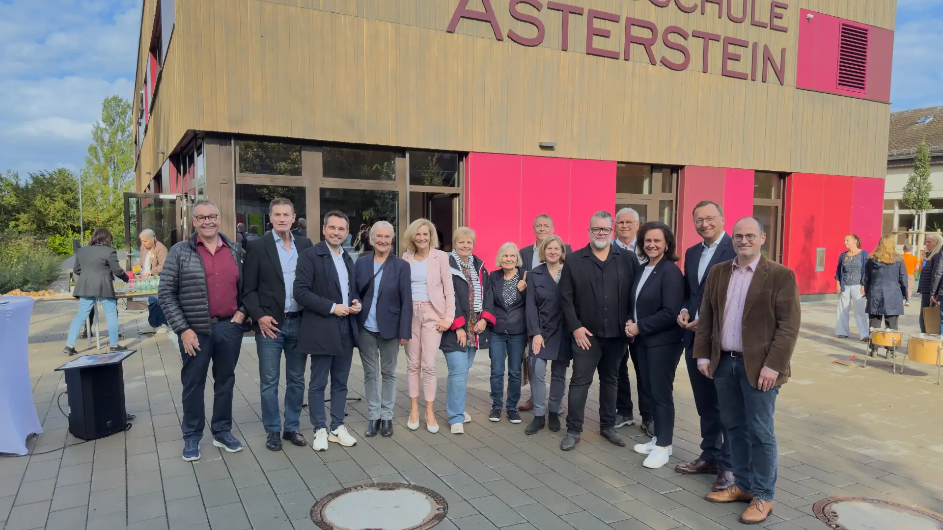 Personengruppe bei der Schlüsselübergabe an der Grundschule Asterstein vor dem Gebäude, mit Oberbürgermeister, Bildungsministerin, Schulleiter und Dezernent.