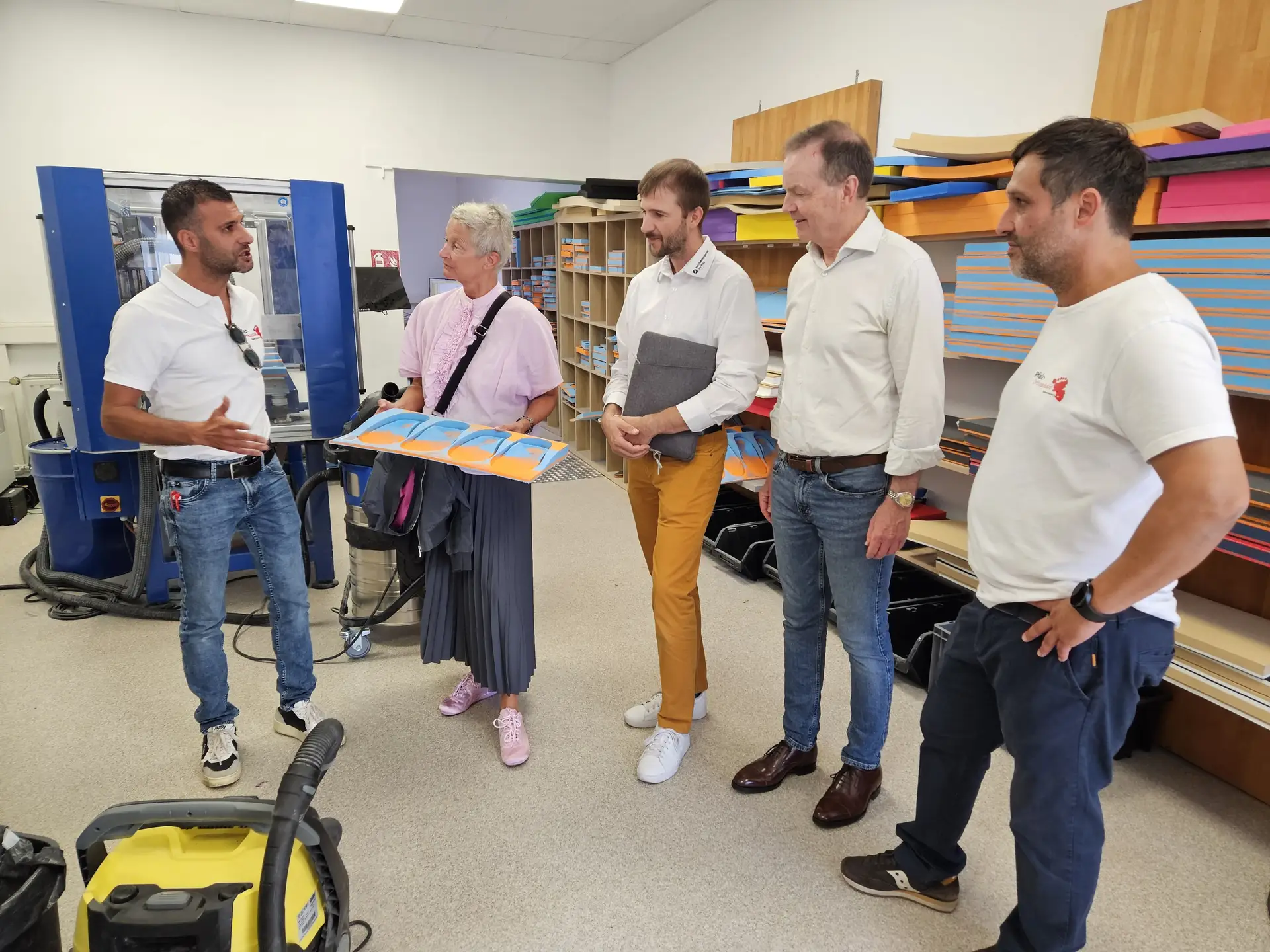 Mehrere Personen stehen gemeinsam in einer Werkstattumgebung bei einem Unternehmensbesuch.