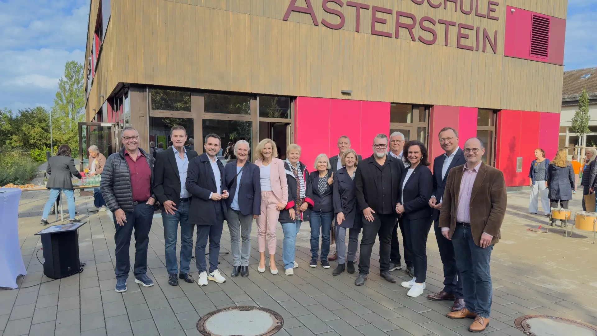 Personengruppe bei der Schlüsselübergabe an der Grundschule Asterstein vor dem Gebäude, mit Oberbürgermeister, Bildungsministerin, Schulleiter und Dezernent.