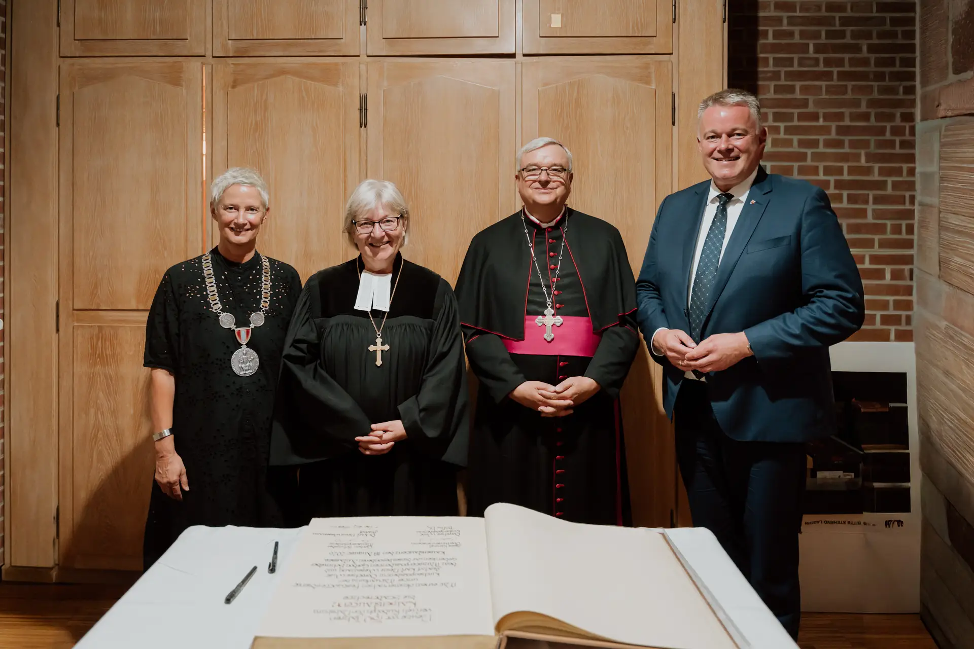 Oberbürgermeisterin Kimmel, Kirchenpräsident Wüst, Bischof Wiesemann und Ministerpräsident Schnieder nach dem Eintrag ins Goldene Buch.