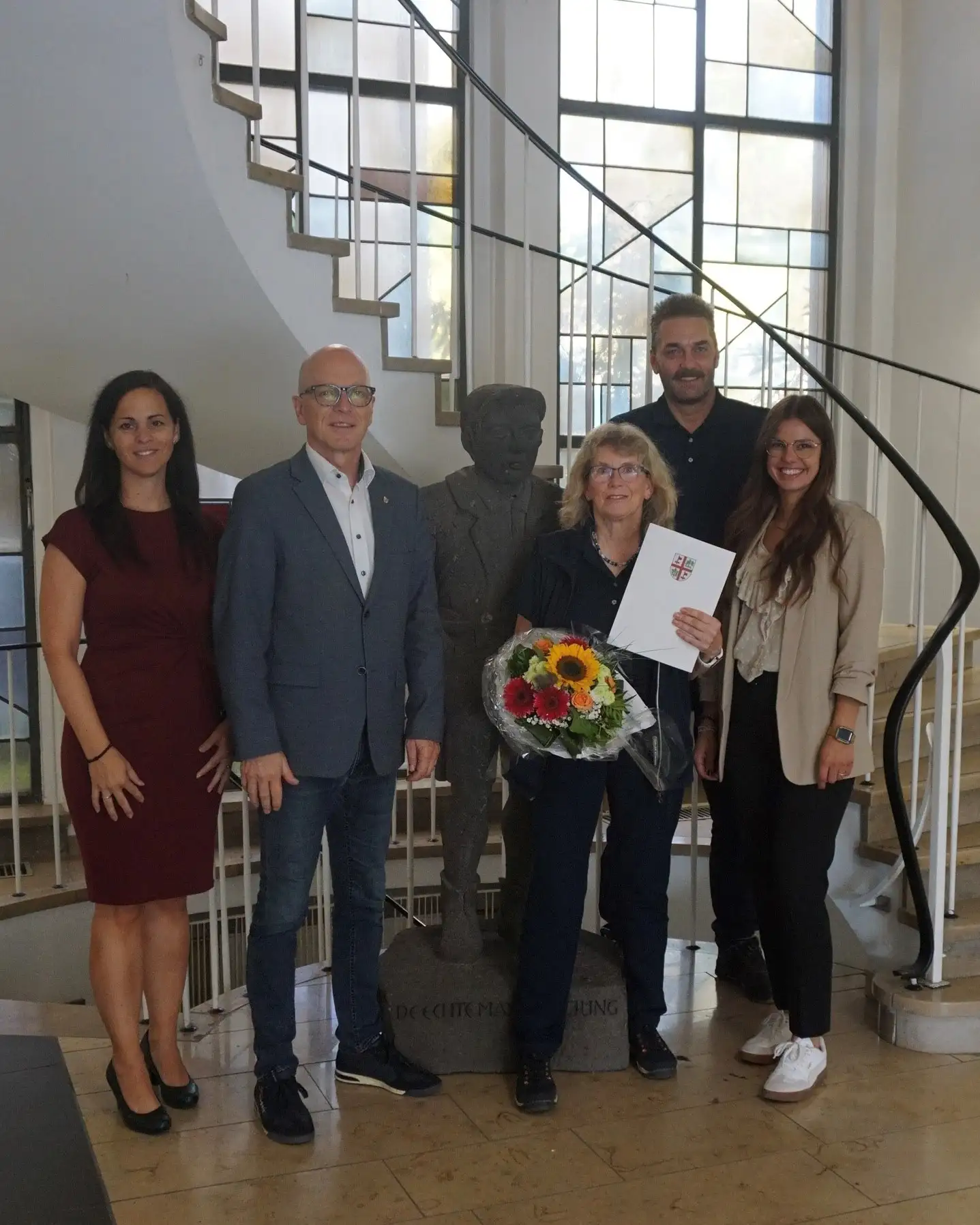 Mehrere Personen stehen nebeneinander und werden bei der Verabschiedung von Claudia Ott in die Altersteilzeit vorgestellt.