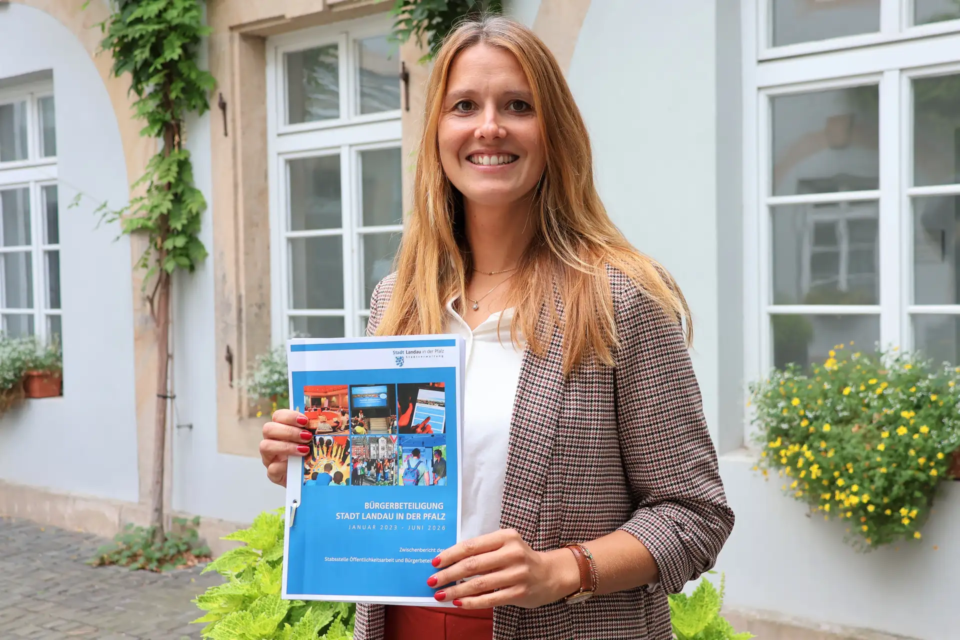 Bürgerbeteiligungsbeauftragte Franziska Ritter präsentiert den aktuellen Zwischenbericht und zeigt, was sich bei der Bürgerbeteiligung in Landau von Januar 2023 bis Juni 2026 getan hat. (Quelle: Stadt Landau)