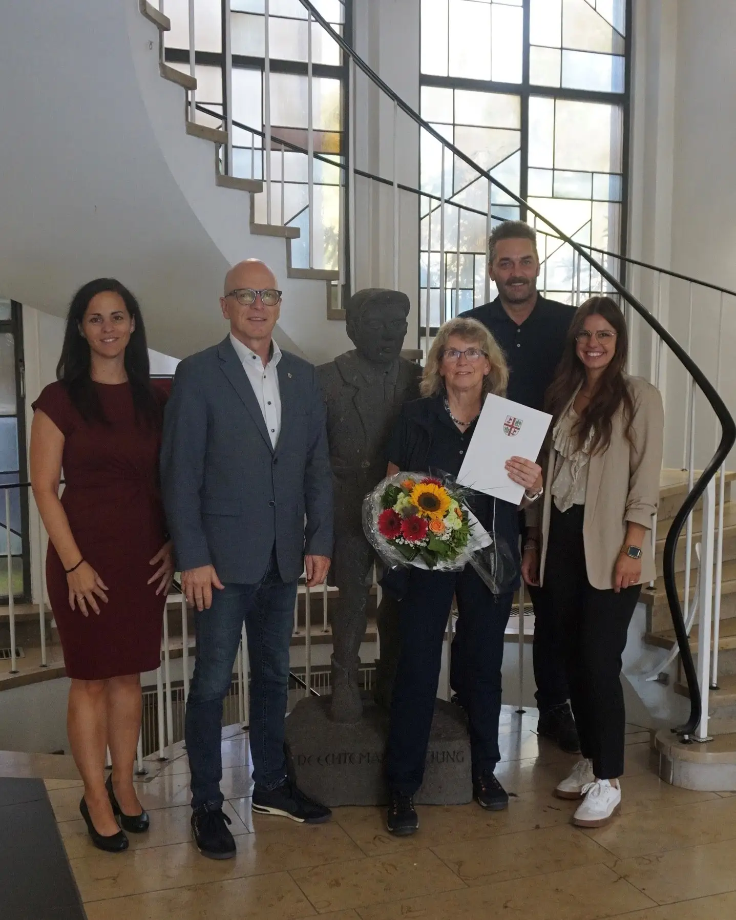 Mehrere Personen stehen nebeneinander und werden bei der Verabschiedung von Claudia Ott in die Altersteilzeit vorgestellt.